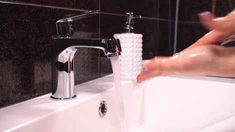 The-girl-takes-the-soap-and-washes-her-hands-in-the-bathroom