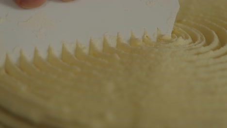 extreme close-up of shaping the frosting on a cake to make a perfect spiral design