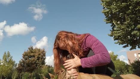 woman stroking her boxer dog in the park
