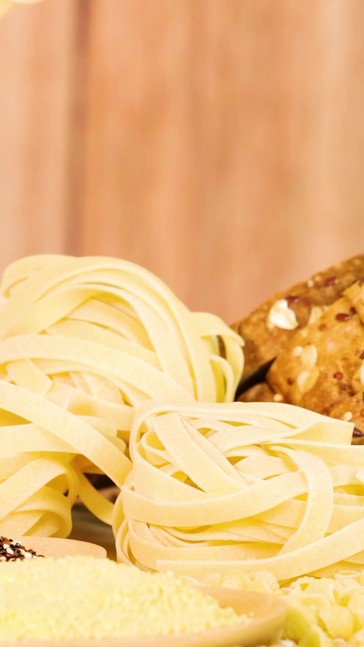 Una mano seleziona le tagliatelle da una pila ben disposta su una superficie di legno, sotto un'illuminazione calda.