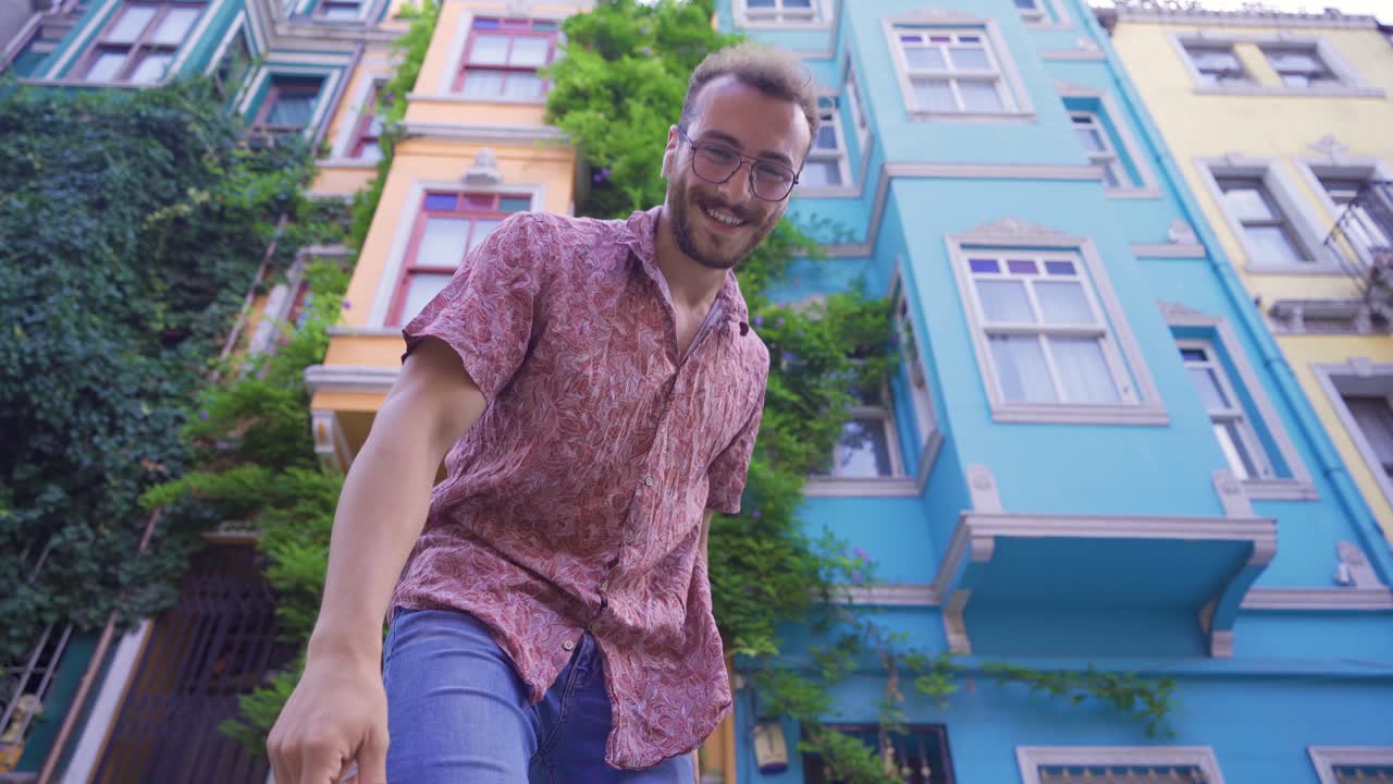 Pohledný mladý muž tančí na ulici s barevnými domy