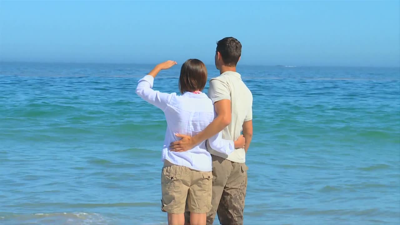 예쁜 젊은 부부가 바다를 바라보고 있습니다.