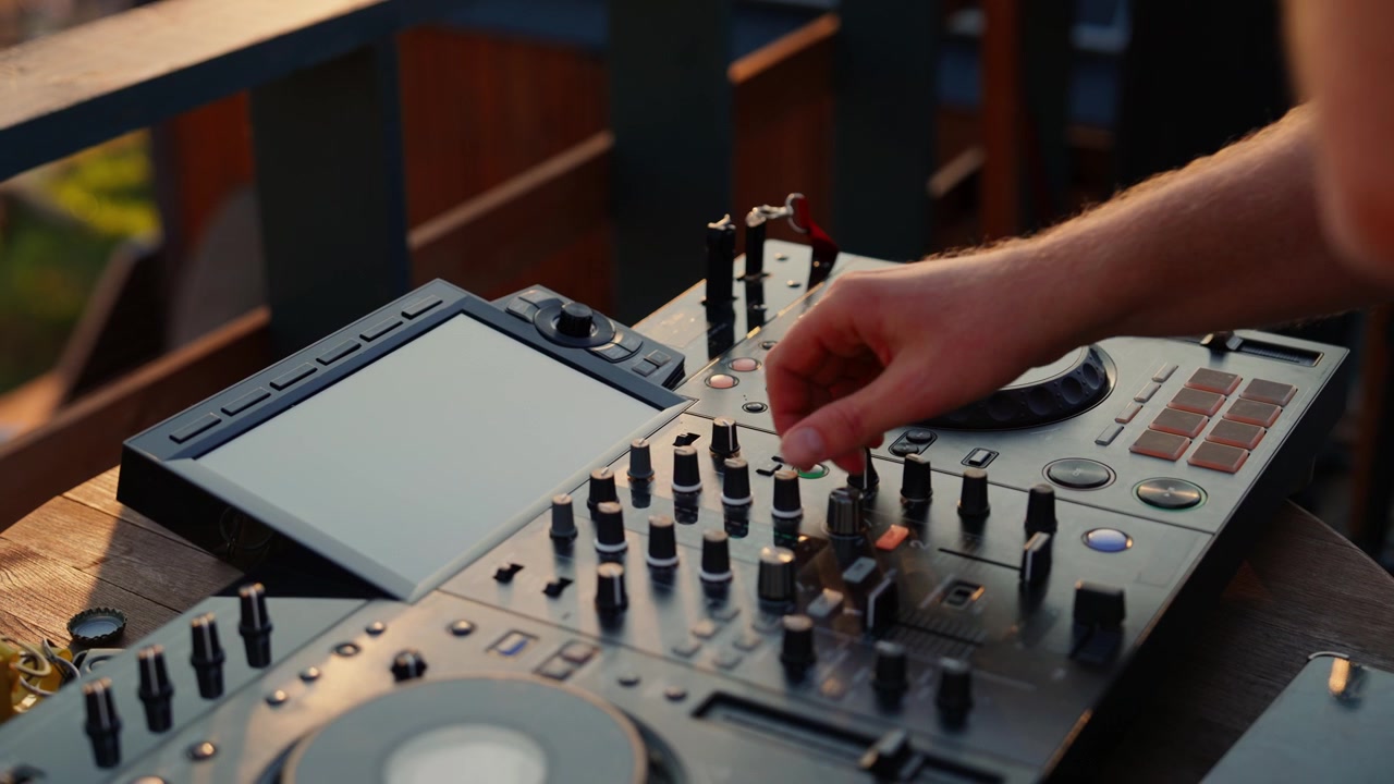 DJ mixant de la musique sur une console professionnelle au coucher du soleil