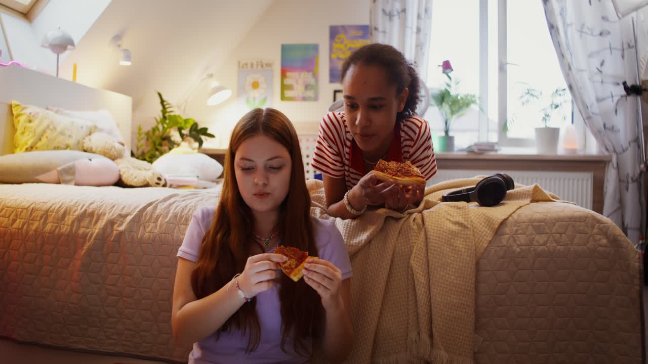 십대 소녀들이 침실에서 피자를 먹고 있습니다.