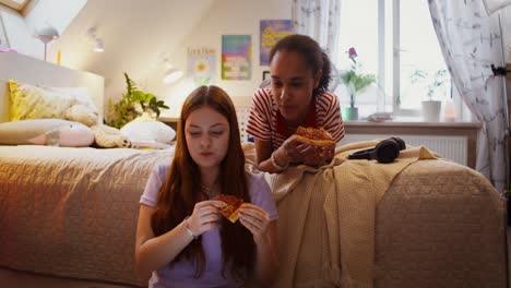 chicas adolescentes comiendo pizza en su dormitorio