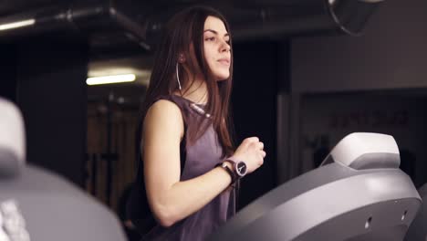 attractive brunette girl with long hair in her 20's wearing dryfit sportswear, running on treadmill.