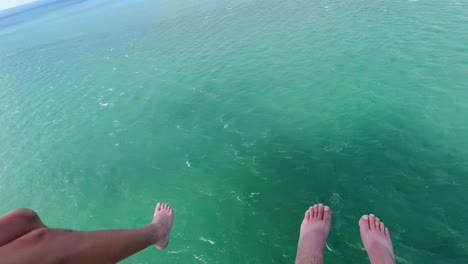 parasail b roll of feet dangling in sky from 2 people parasailing with green and blue ocean water below them in the florida keys