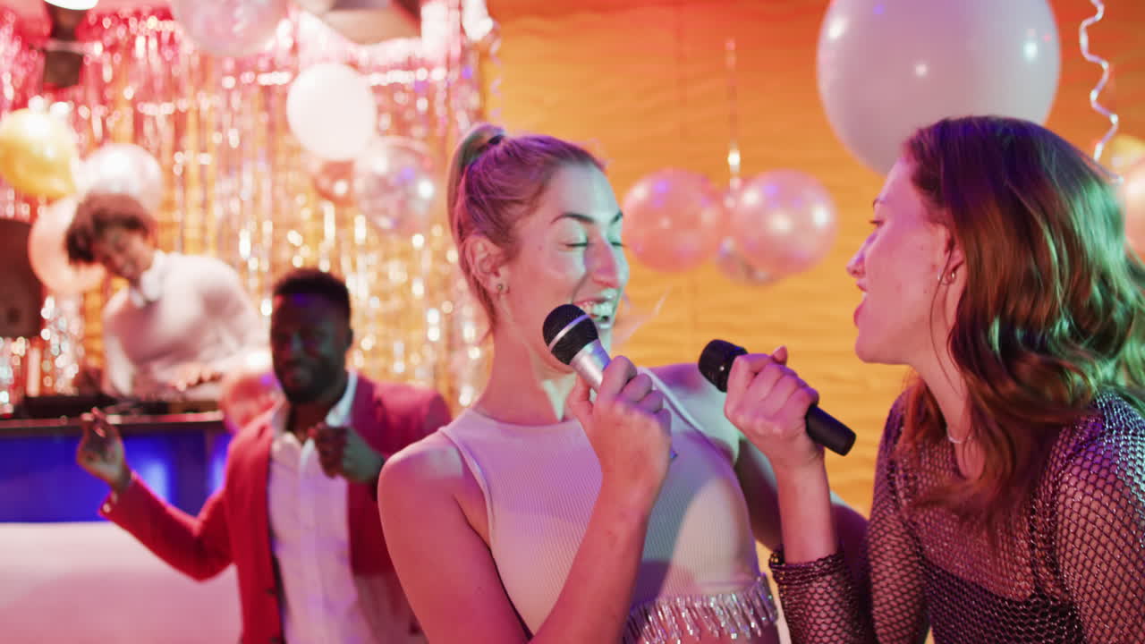 Video of two happy caucasian female friends singing karaoke at a nightclub bar