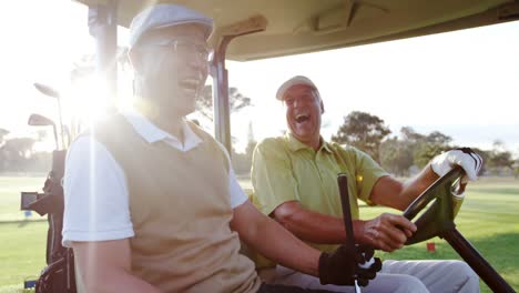 Two-golfers-laughing-together-in-their-golf-buggy