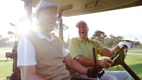 Dos-Golfistas-Riendo-Juntos-En-Su-Carrito-De-Golf.