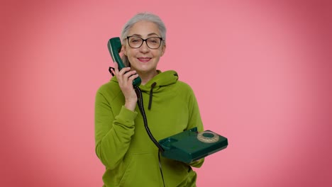 Senior-granny-gray-haired-woman-talking-on-wired-vintage-telephone-of-80s,-says-hey-you-call-me-back