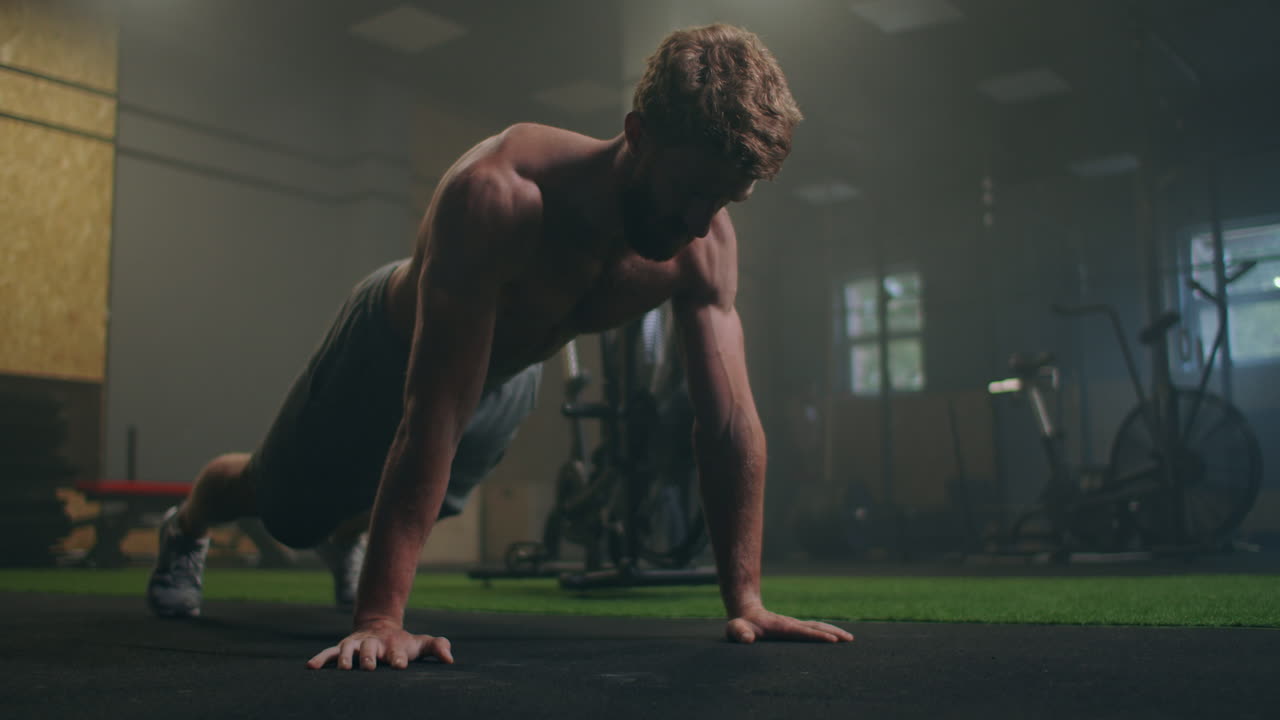 hombre haciendo flexiones en un gimnasio. exhalación e inhalación después de flexiones y ejercicio. perfecto para el acondicionamiento físico y el entrenamiento. joven deportista realiza flexiones en el gimnasio. el atleta está involucrado en fitness