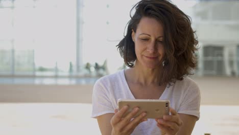 una mujer morena sonriente usando un teléfono inteligente.