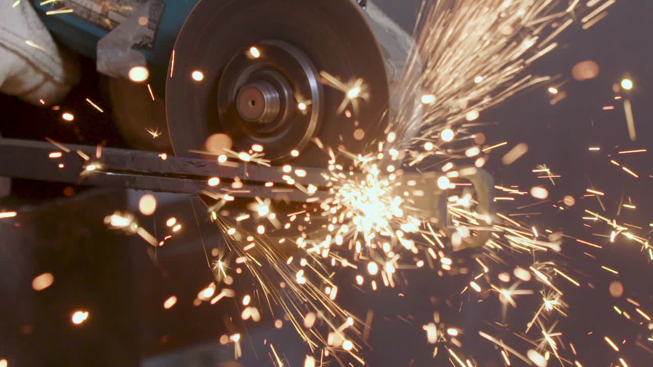 кузнец режет стальной металл с помощью шлифовальной пилы