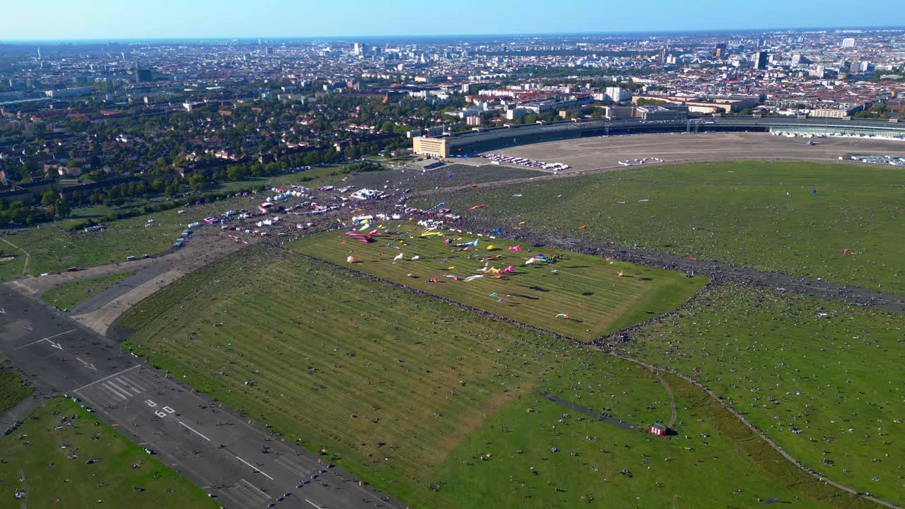 thousands of Berliners enjoying the giant kite festival on a sunny day at Tempelhofer Feld, the former Tempelhof Airport. Great aerial view flight drone camera pointing down