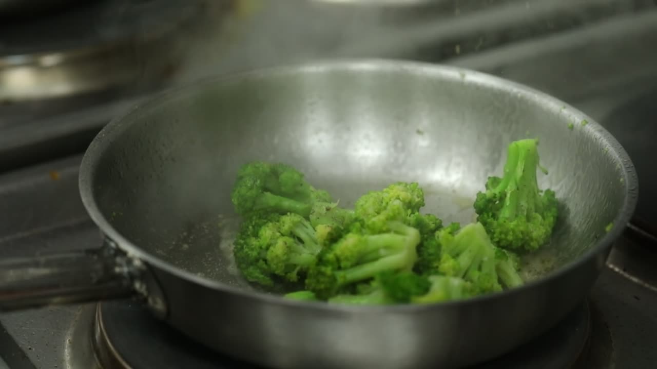 A Chief cooks broccoli on a grill close up shot, insert shot