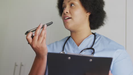 video of focused plus size african american female doctor using smartphone