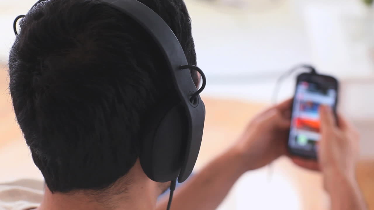 스마트폰에서 음악을 선택하는 헤드폰을 가진 잘생긴 남자