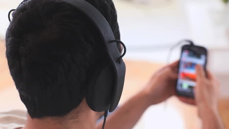 handsome man with headphones choosing music on his smartphone