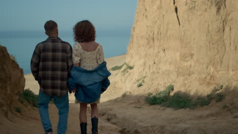 pair walking down seacoast to empty beach. happy couple going on ocean shore.