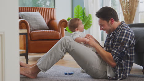 Loving-Transgender-Father-Playing-Peek-A-Boo-With-Baby-Son-Sitting-On-Floor-At-Home