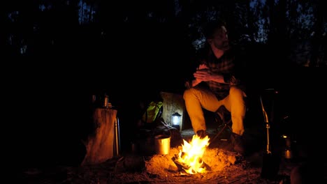 Man-sitting-near-campfire-in-the-forest-4k