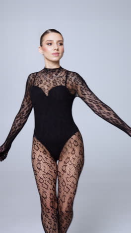 sexy caucasian model wearing black seductive outfit walks and turns in studio. lingerie and underwear. vertical video.