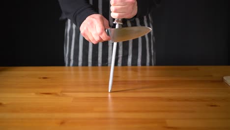 cámara lenta de un chef hombre usando varias técnicas para afilar un cuchillo con las manos, usando un cuchillo profesional y un acero afilado de diamantes