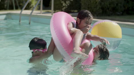 Niños-Alegres-Jugando-Con-Un-Anillo-Inflable-En-La-Piscina-Al-Aire-Libre.