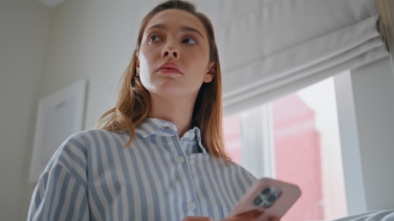 Pensive woman messaging bedroom using smartphone closeup. Girl browsing phone