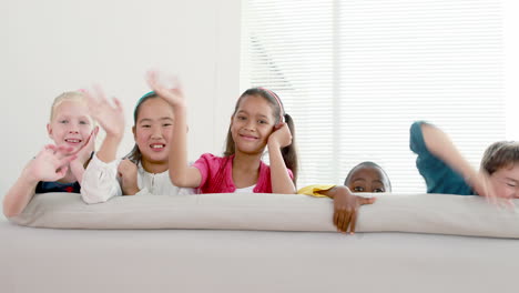 cute children waving and smiling at camera on the sofa