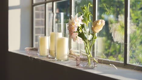 Schöne-Blumen-Und-Kerzen,-Die-Auf-Einem-Fensterbrett-Sitzen