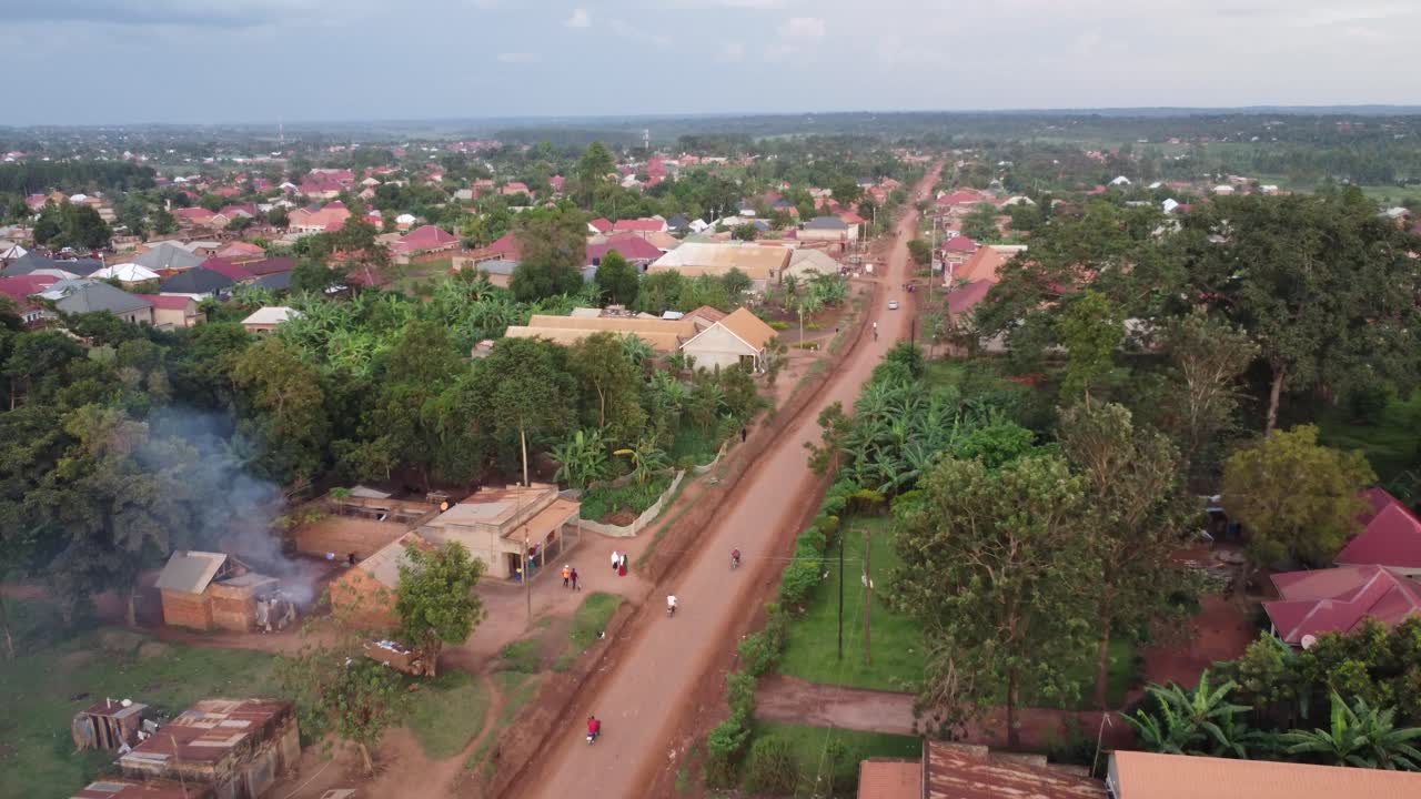 Drone shot of rural villagers commuting on a dirt road in Uganda, Africa