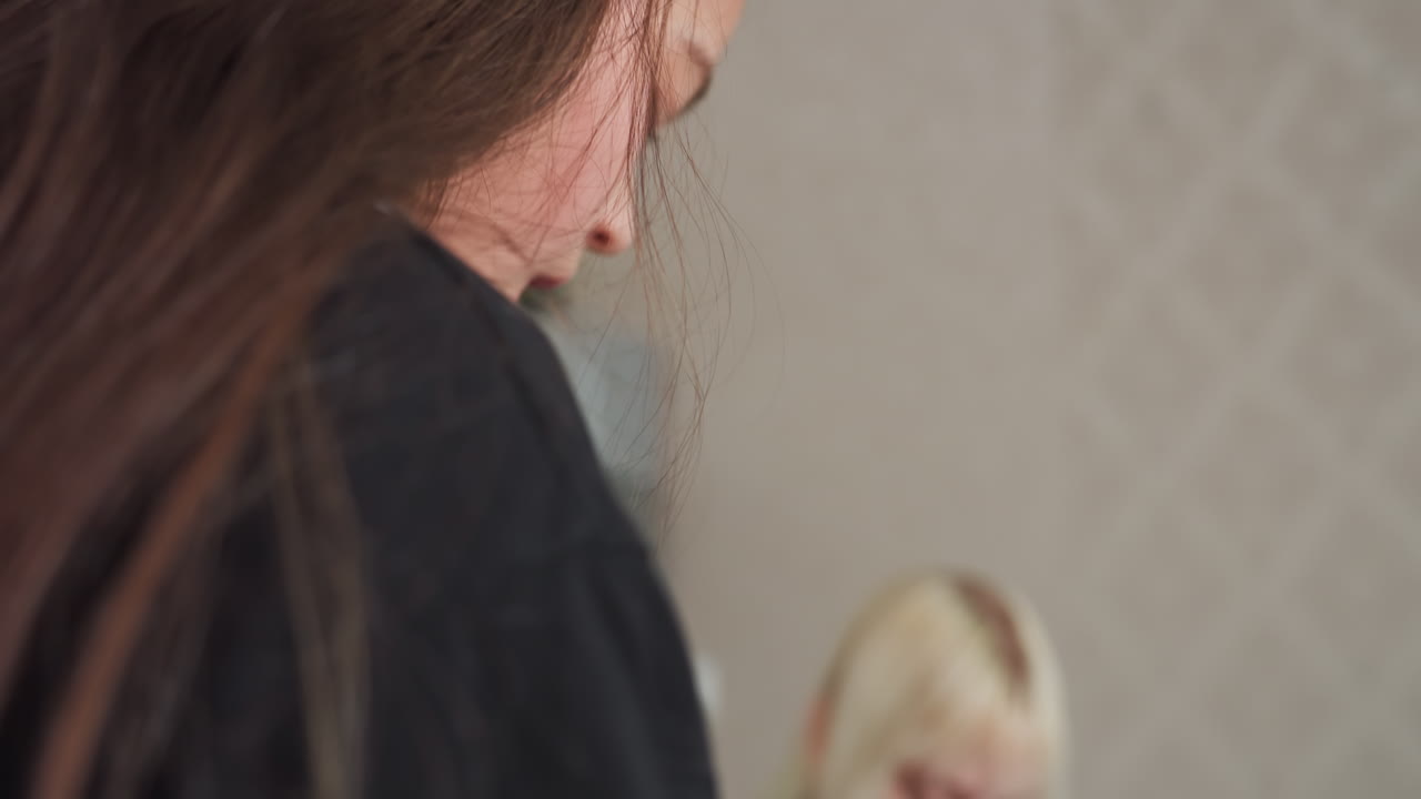 friends in kitchen enjoying snack together, one seated eating, fridge and microwave in background, casual indoor activity, young women sharing moment, light and bright kitchen environment