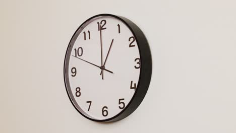 a close-up 4k shot of a black and white wall clock filling the frame, showing the time as 1:00.