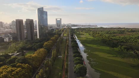 aerial along street between skyscrapers and greenlands in buenos aires