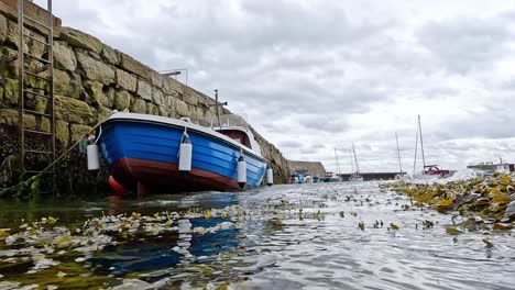 blue boat docked by stone wall in fife