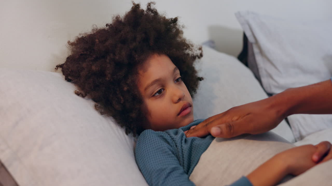 A parent comforting a sick child sleeping in bed