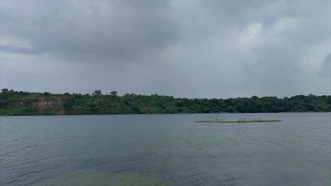 stunning view of mahisagar river flowing, surrounded by lush greenery and cloudy skies during india's monsoon season, beauty of nature.