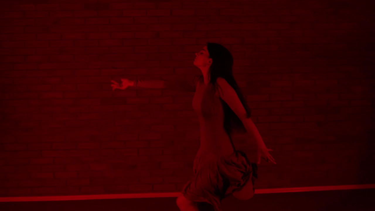 Ballerina attraente che danza in una stanza rossa