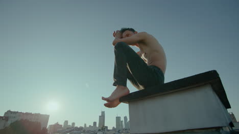 shirtless man in deep though on rooftop, cinematic slow motion