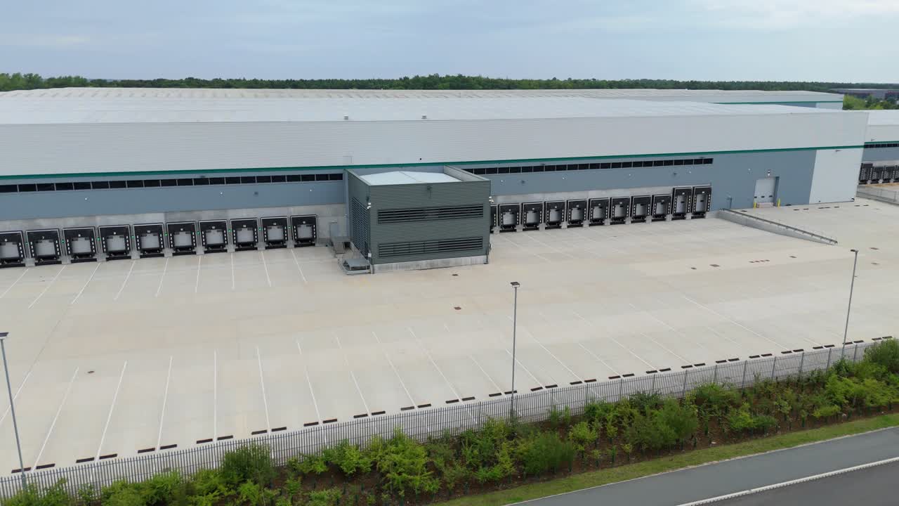 Aerial drone cinematic close up footage of new industrial warehouse distribution centre with loading bays in Kettering England UK