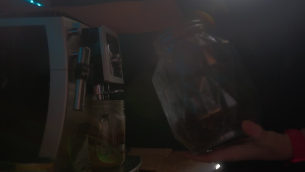 primer plano de una máquina de café con un frasco de vidrio de granos de café que se vierte