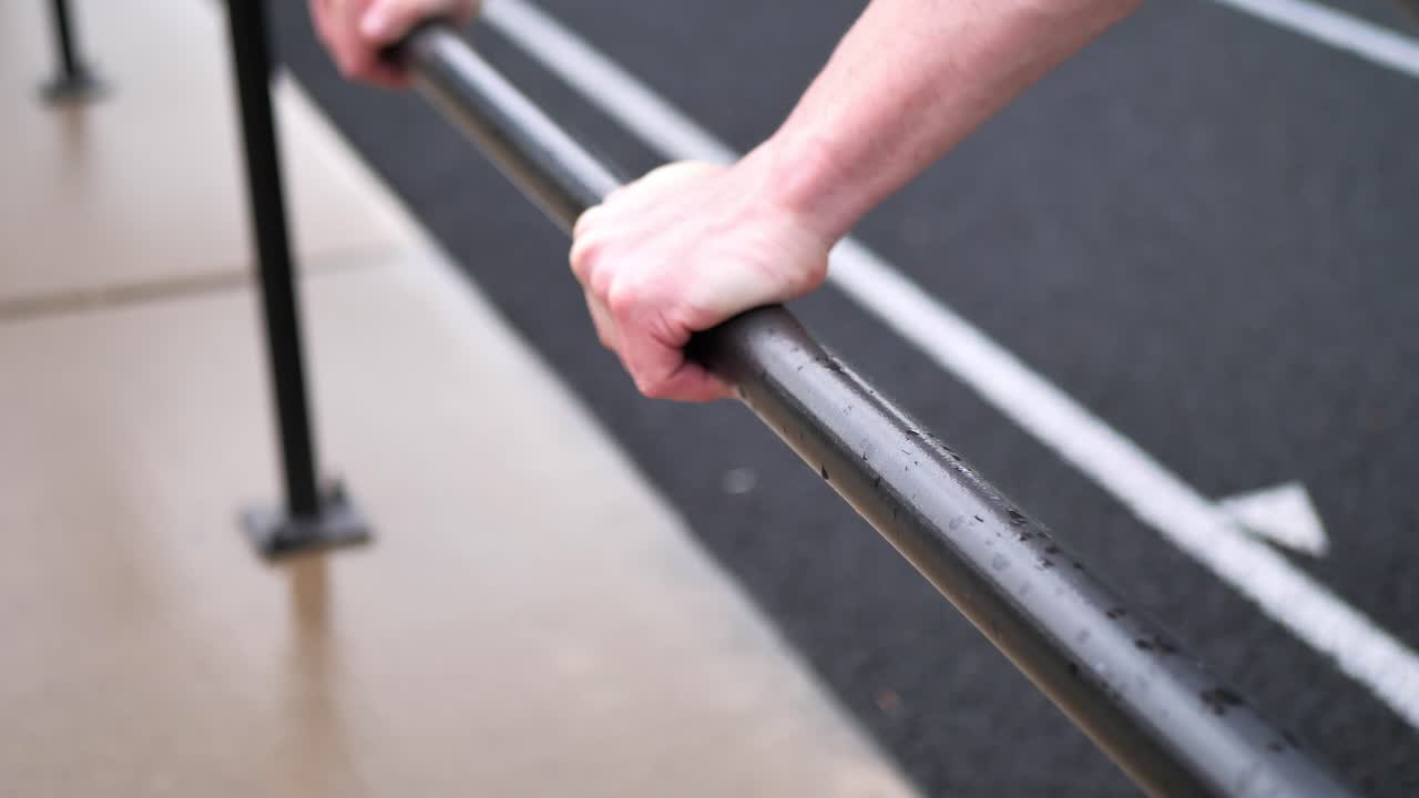 Close-up of hands gripping a metal bar during an outdoor workout