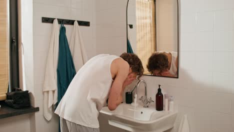 man washing his face in a bathroom