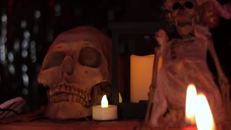 cráneo humano, muñeca esqueleto y velas encendidas en la oscuridad, dia de muertos