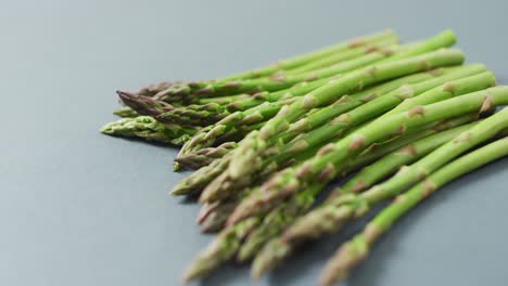 video of close up of fresh asparagus over grey background