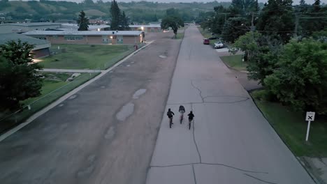 Three-young-kids-ride-their-bikes-through-a-pretty-urban-area-during-sunset