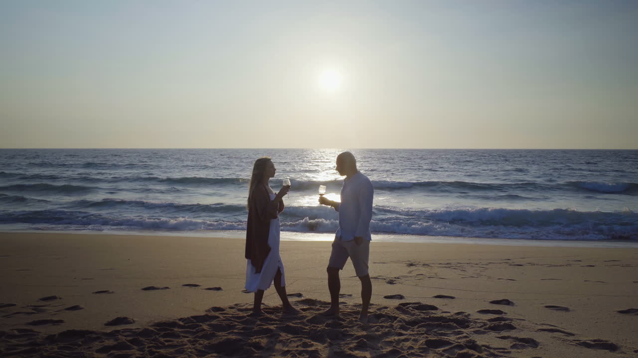 Couple drinking wine on beach at sunset | Premium Stock Video Footage