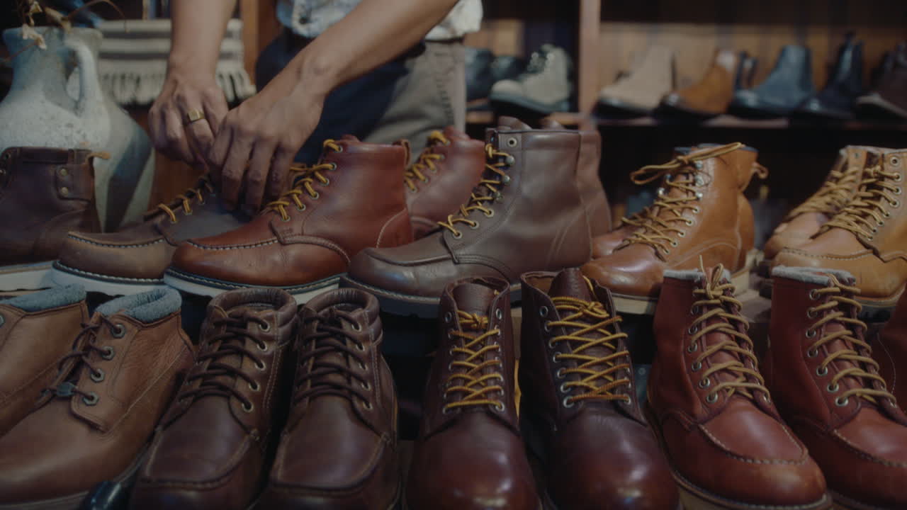 Asiatischer Schuster schnürt restaurierte Lederstiefel in einem Vintage-Laden.